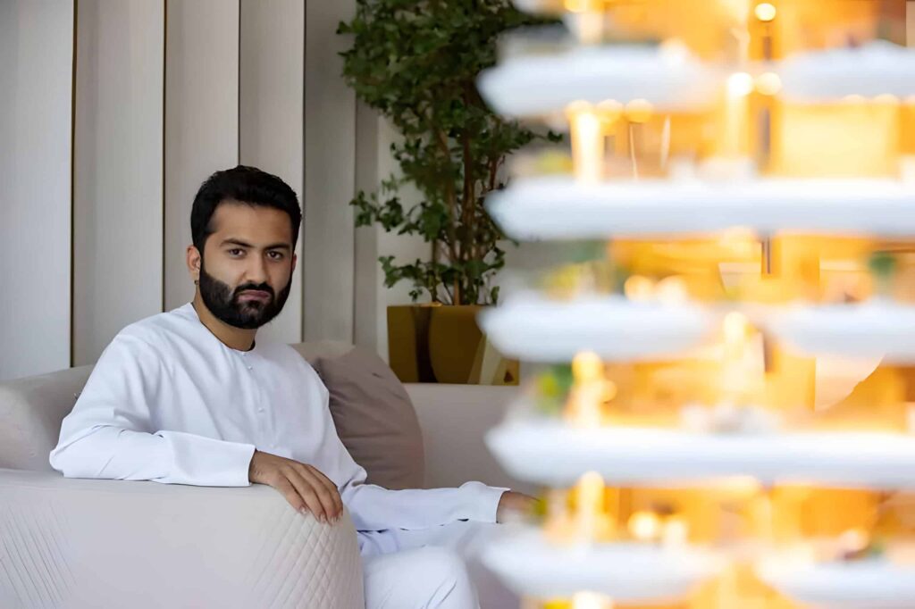 Abbas Sajwani, founder and CEO of AHS Properties, seated in white traditional Emirati dress beside a luxury tower model